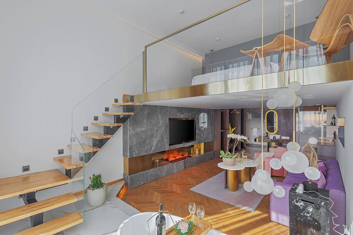 Un interior moderno con una escalera, una chimenea, un sofá y una zona de comedor.