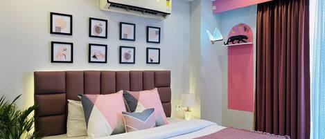 Una habitación de hotel moderna con una cama grande, un ventilador de techo, un equipo de aire acondicionado y varias obras de arte enmarcadas en la pared.