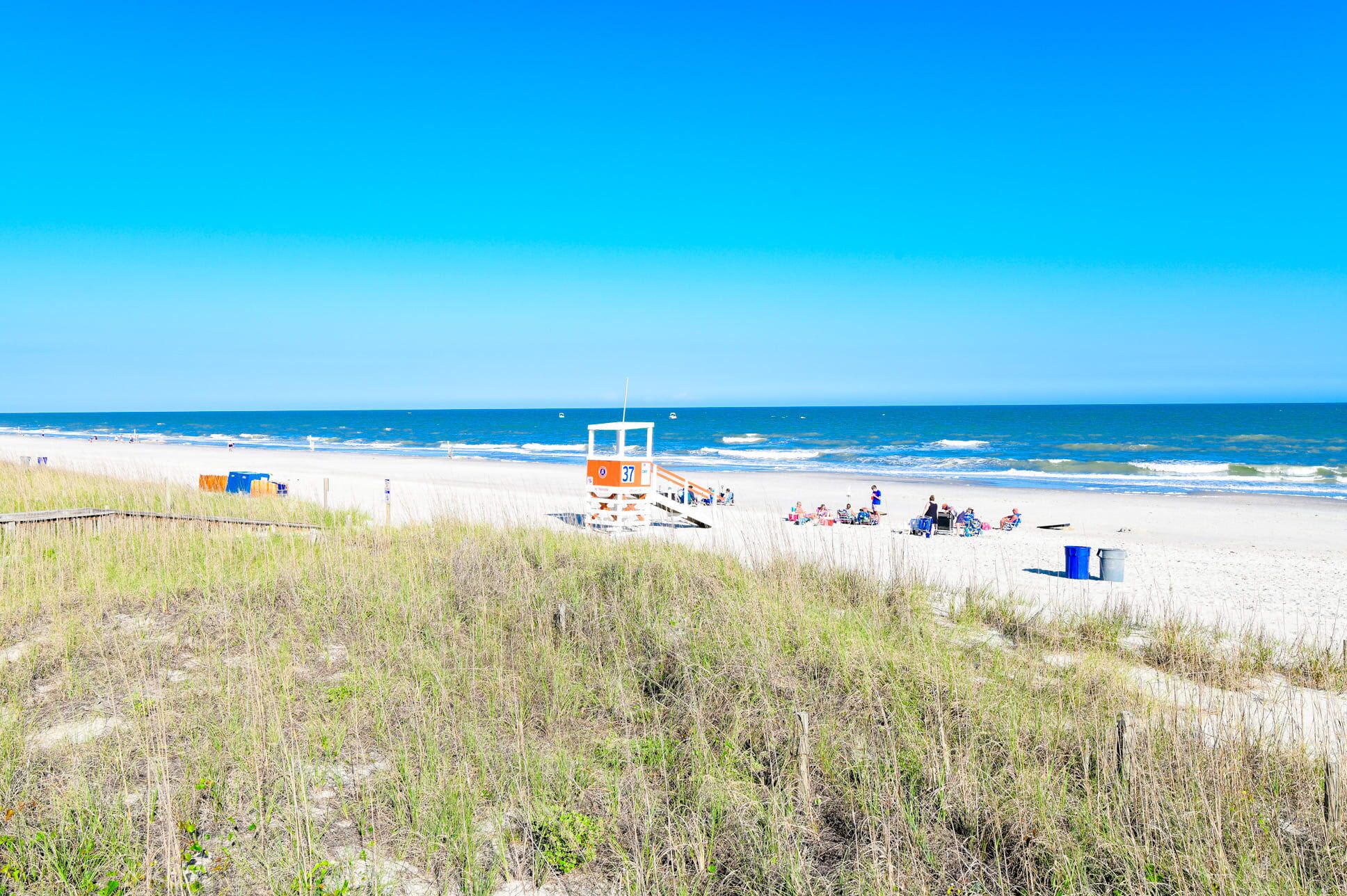 A beach with a lifeguard tower, beach chairs, and umbrellas.