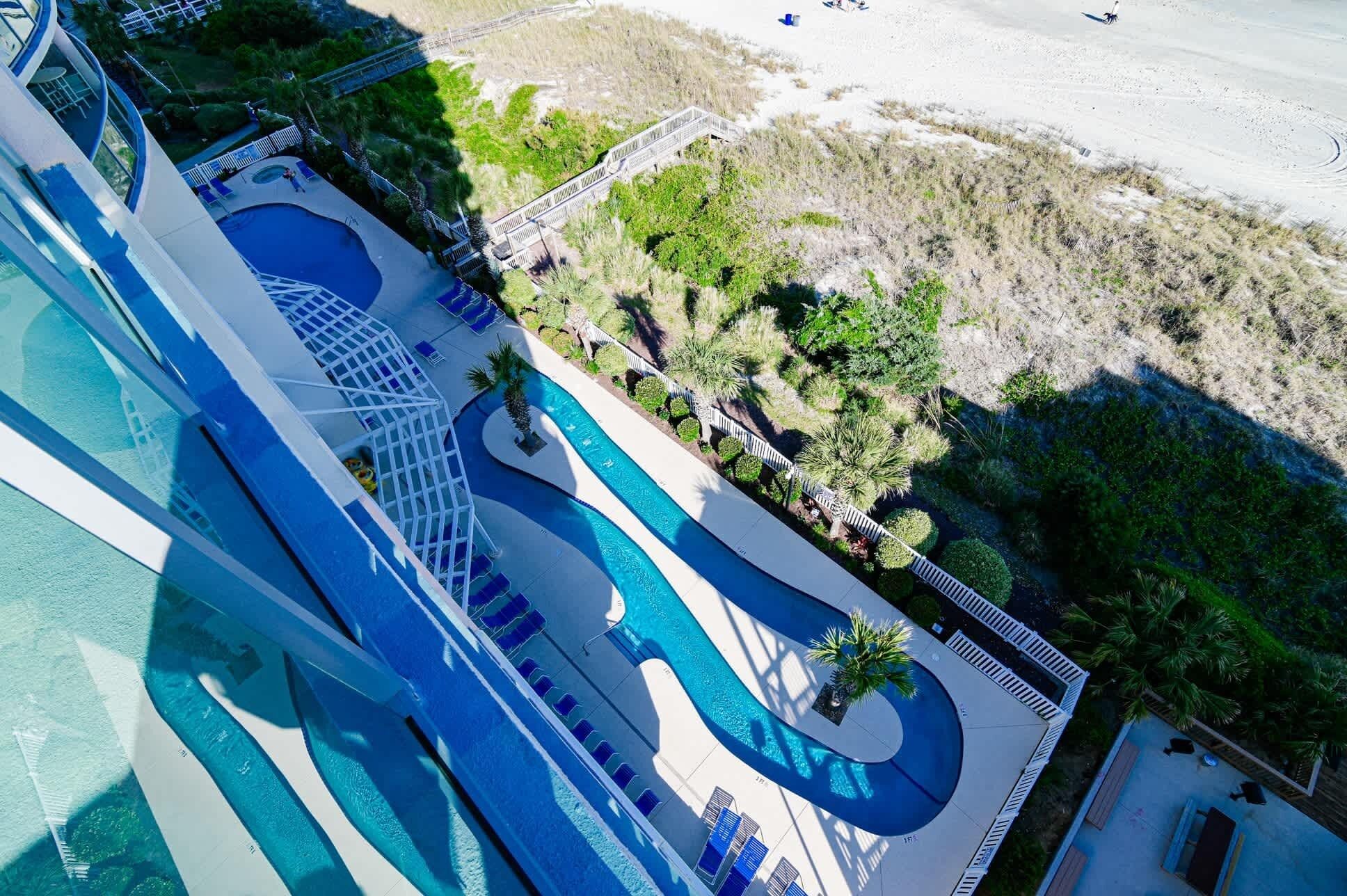 A resort with a large pool area, a beach, and a bridge connecting different sections.
