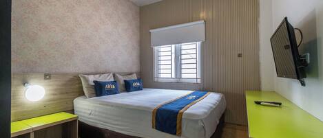 A hotel room with a bed, a desk, a television, and a window.