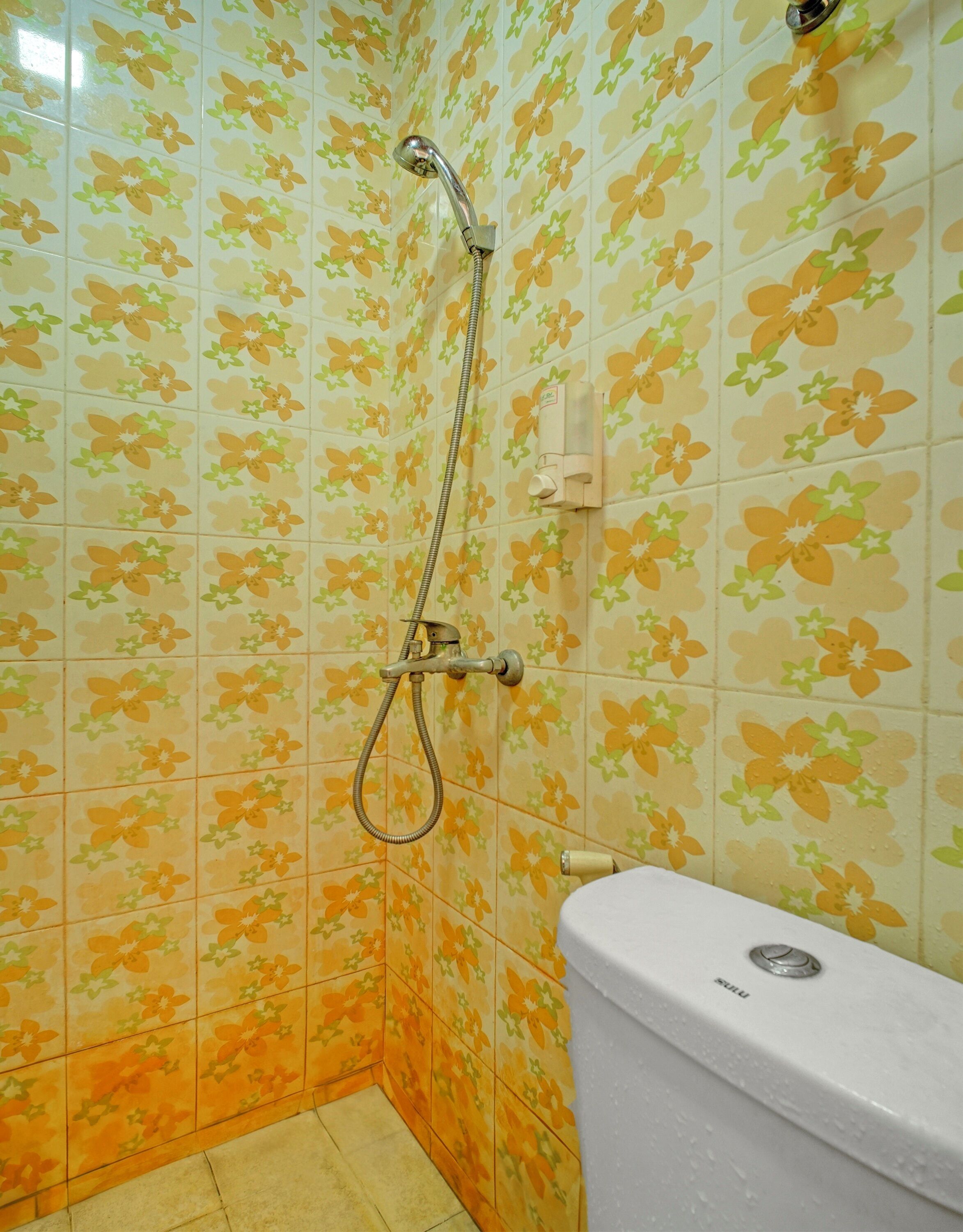 A bathroom with floral patterned tiles, a shower, and a toilet.