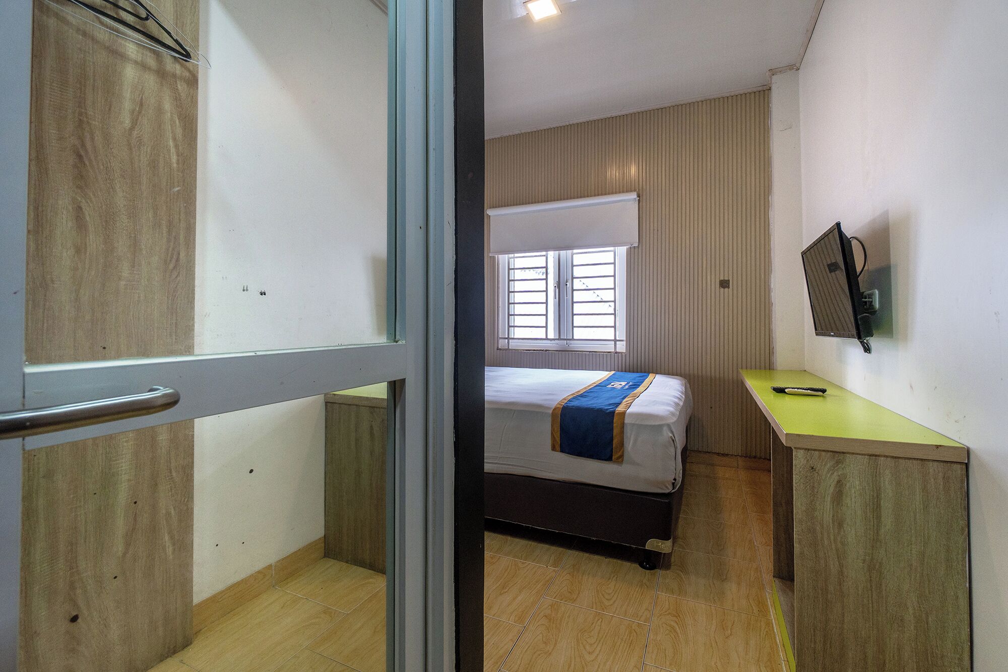 Une chambre avec un lit, un bureau, une fenêtre et un téléviseur.