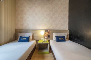 A hotel room with two beds, a nightstand with a phone, a wall clock, and a floral wallpaper. - Hotel Dahlia By ARBA (Jakarta)