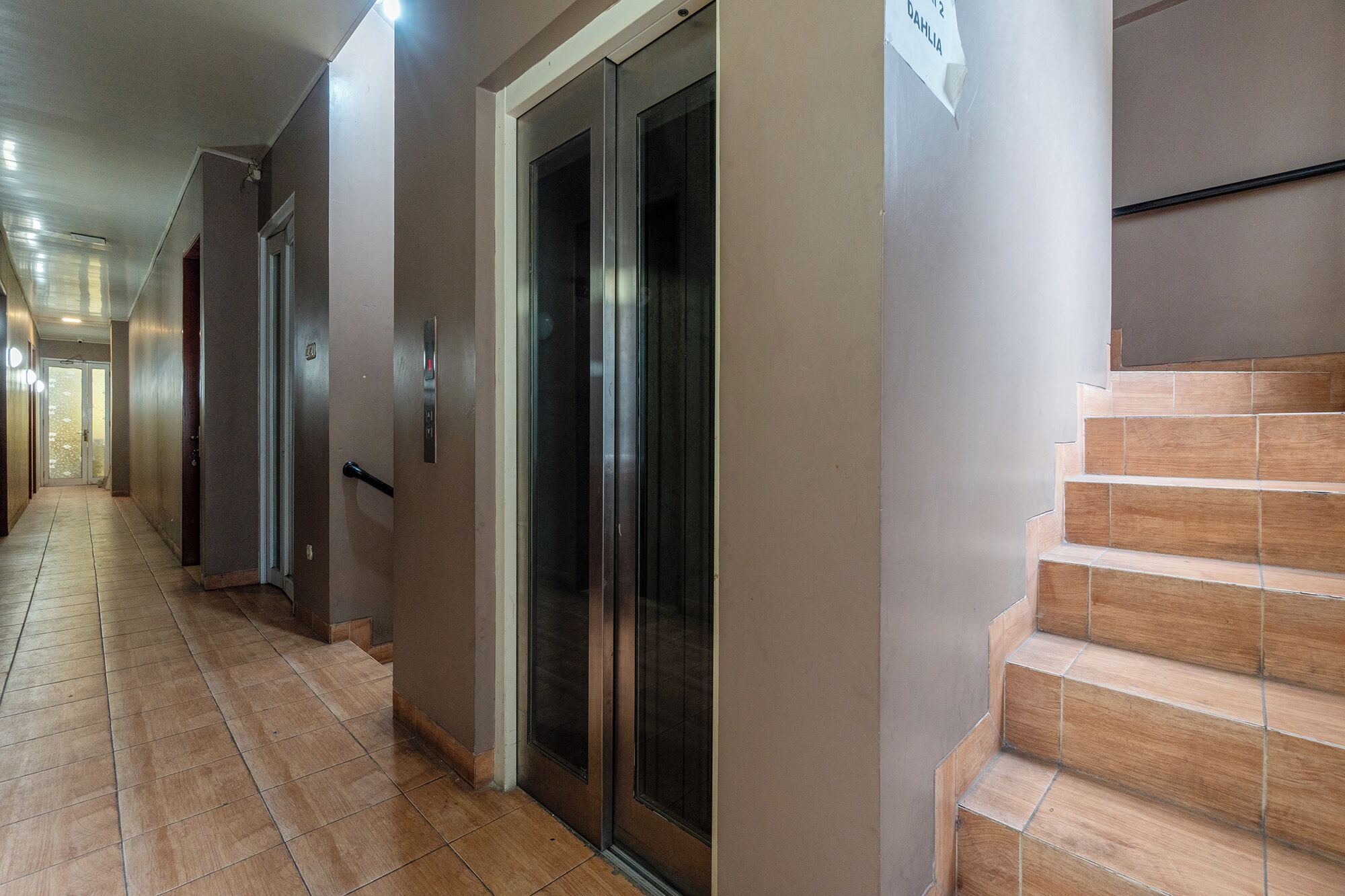 Um corredor com escadas, portas e um elevador.