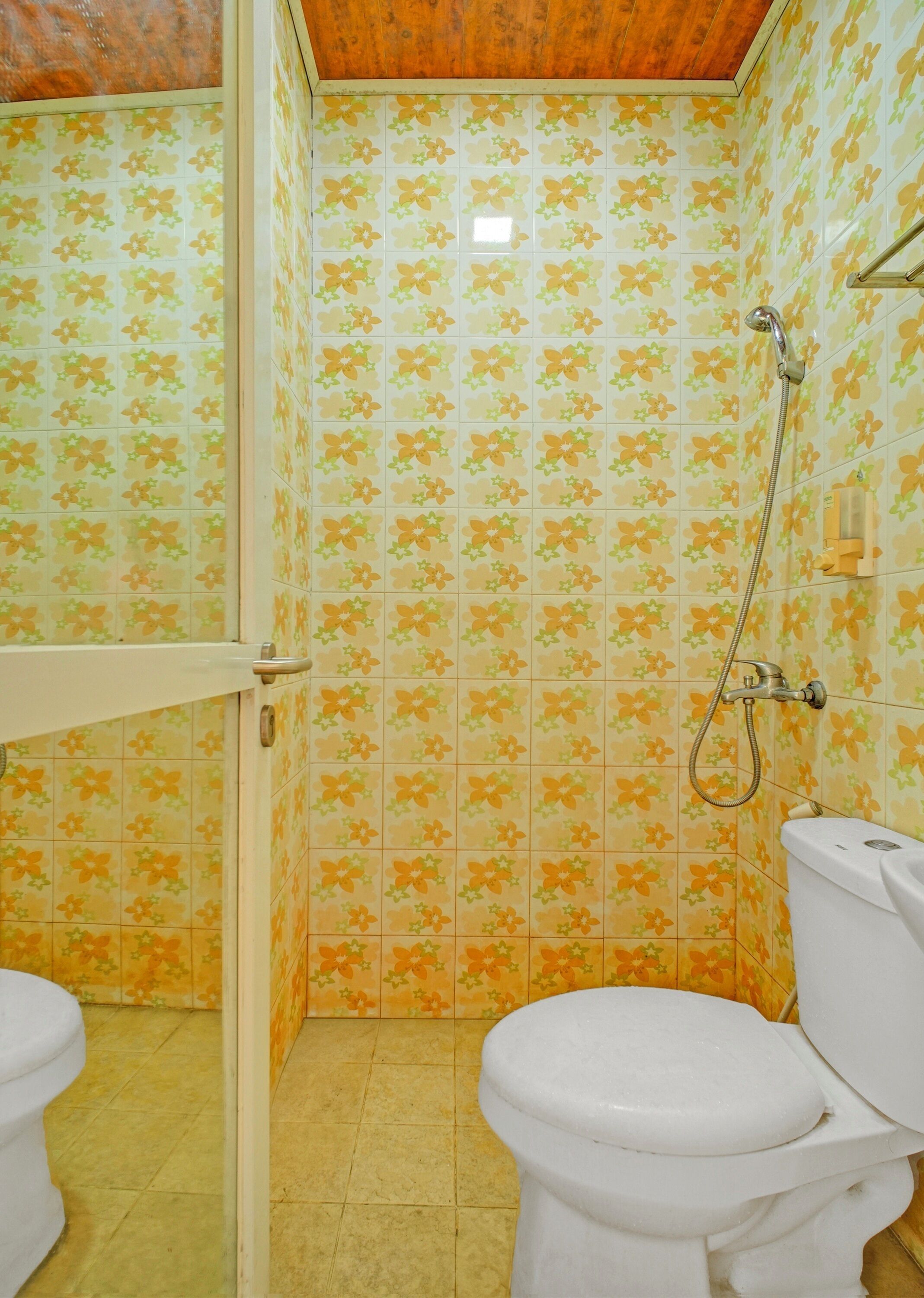 A bathroom with floral patterned tiles, a shower, and two toilets.