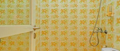 A bathroom with floral patterned tiles, a shower, and two toilets.