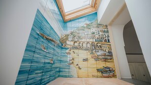 A room with a mural depicting a coastal scene, a skylight, and a tiled floor. - Casa Blue Torricella by Elite Villas (Atrani)