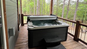 A wooden deck with a hot tub, surrounded by a railing and overlooking a forested area. - Eagle Forest-Sleeps 4, Hot Tub, Fireplace (Broken Bow)