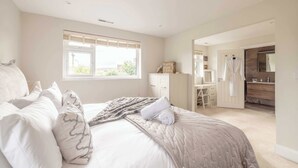 A bedroom with a bed, a desk, and a bathroom. - Windsor Charm : Spacious 4-Bed, Parking & Garden (Berkshire)