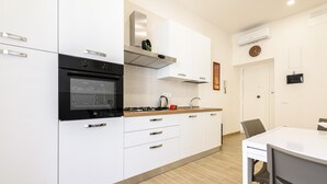 A modern kitchen with white cabinets, a black oven, a stainless steel range hood, and a wooden countertop.