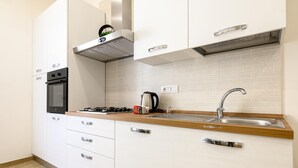 A modern kitchen with white cabinets, a stainless steel sink, and a built-in oven.