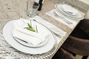 A neatly arranged dining table with white plates, napkins, and a glass of water. - Chic Haven Studio in Kingston (Kingston)