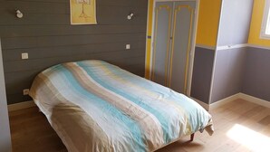Un dormitorio con una cama, un cuadro en la pared, un armario y una ventana.