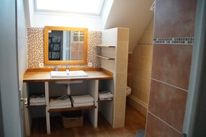 Un baño pequeño con tragaluz, un lavamanos blanco y un salpicadero de azulejos.