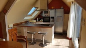 Una cocina compacta con una isla central, microondas, refrigerador y tragaluz.