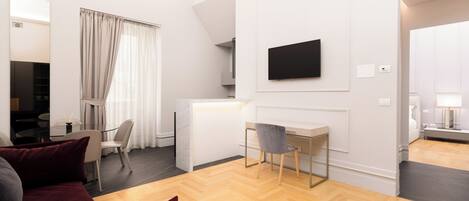 A modern living room with a sofa, a desk, and a TV mounted on the wall.