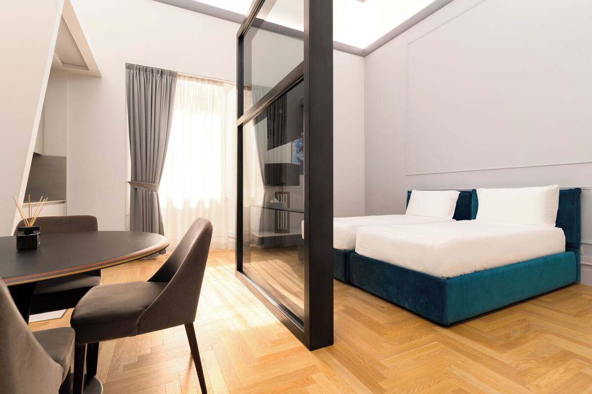 A modern hotel room with a bed, a desk, and a chair.