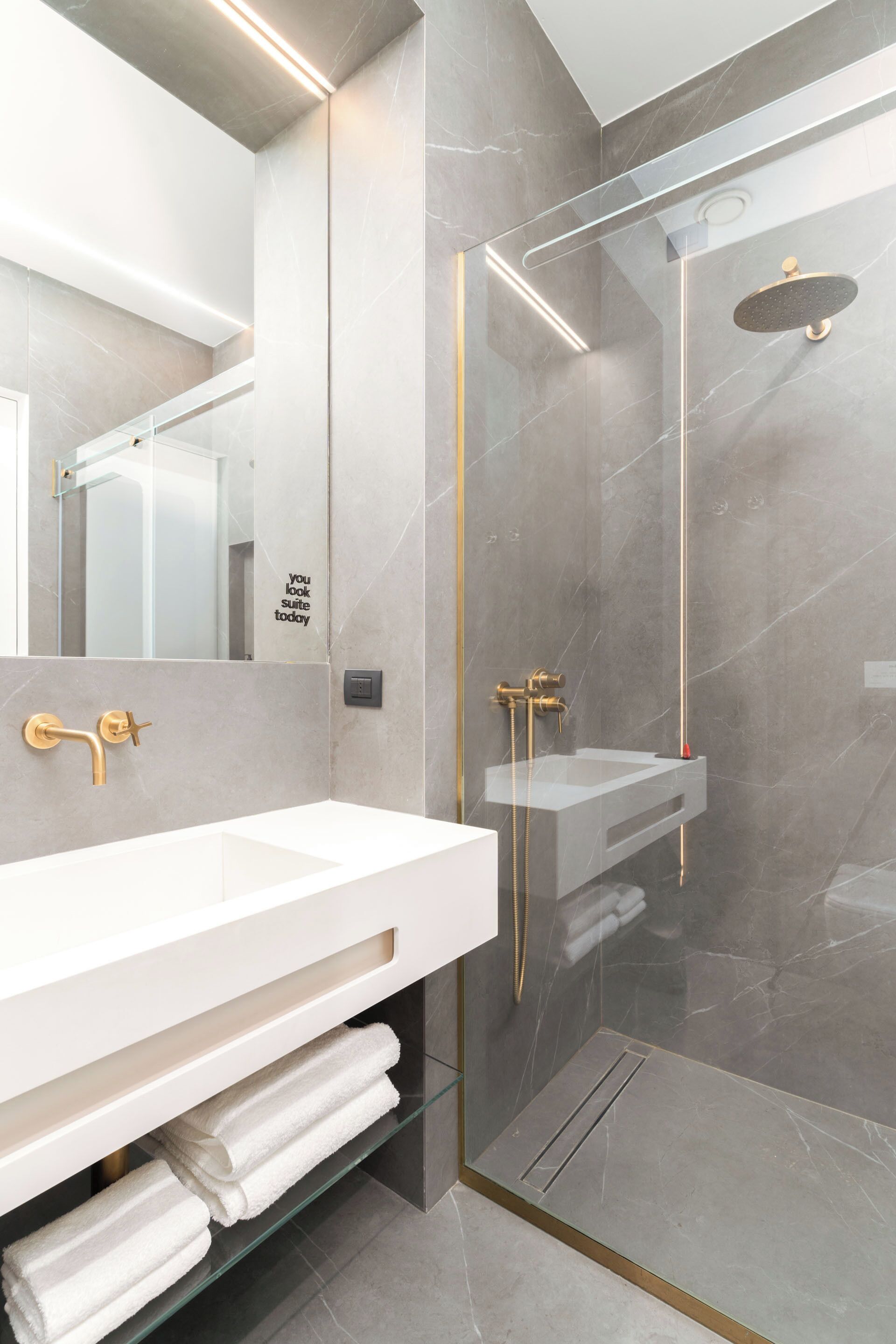 Un baño moderno con ducha de vidrio, un lavamanos blanco y un espejo.