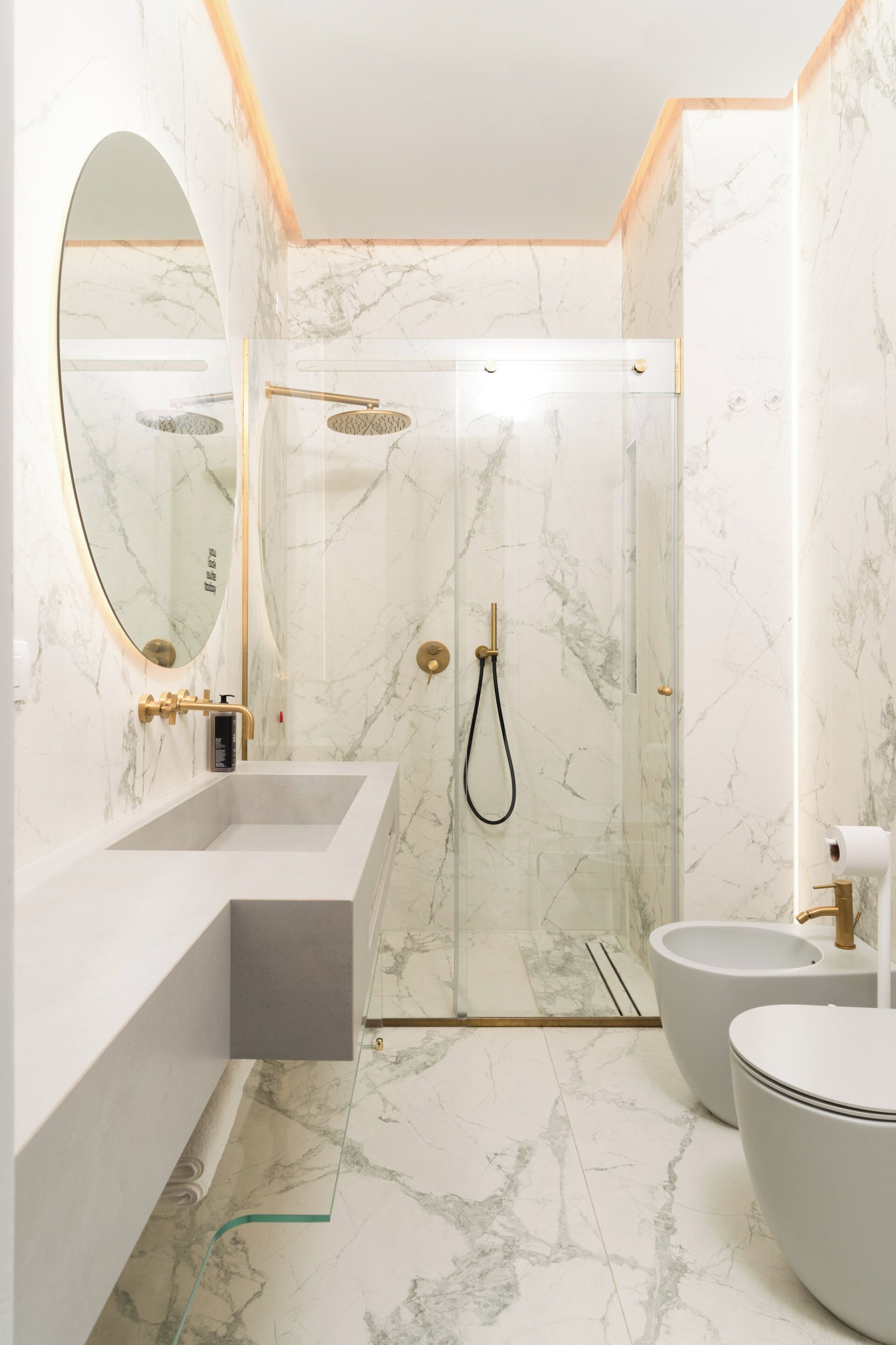 A modern bathroom with a glass-enclosed shower, a large mirror, and a white sink.