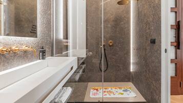 Une salle de bain moderne avec une douche à parois de verre, un meuble-lavabo blanc et un porte-serviettes.