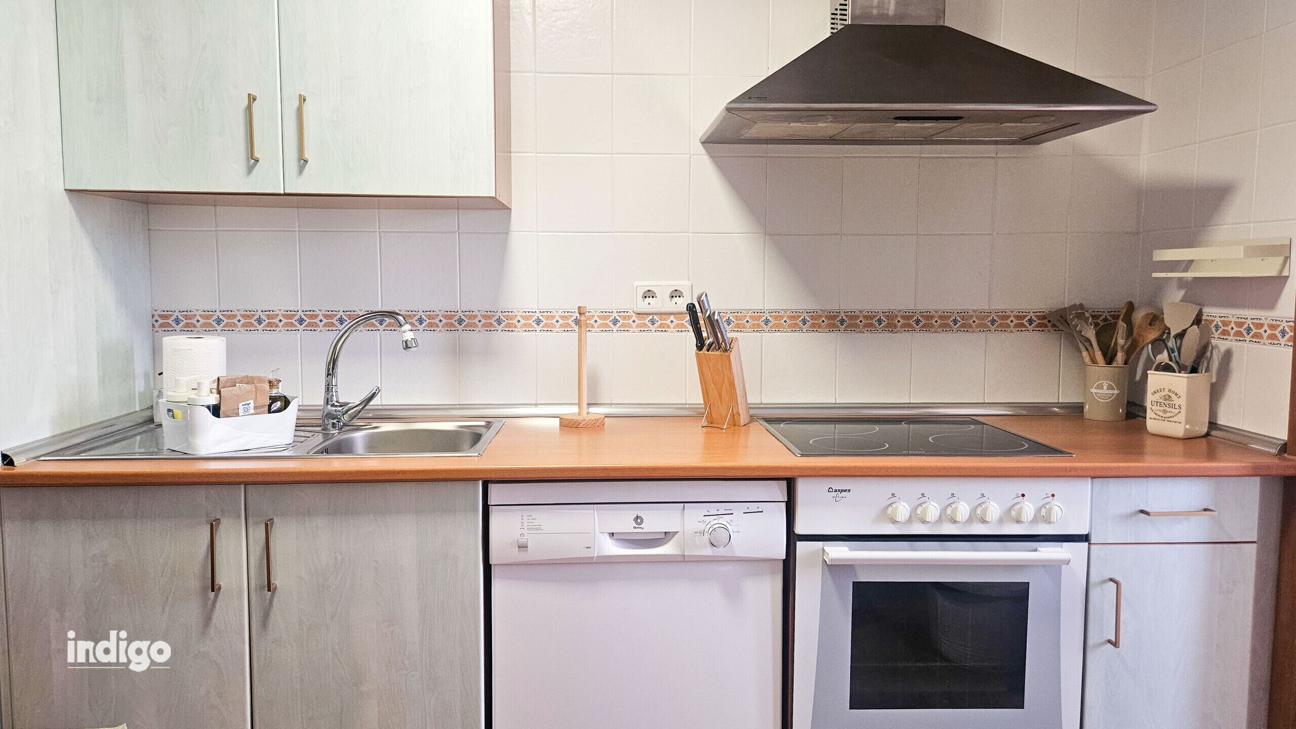 A kitchen with a dishwasher, oven, sink, and a stove.