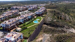 A residential area with multiple two-story buildings, a swimming pool, and a surrounding hilly landscape. - Pleasant apartment with great views JUL01 (Ayamonte)