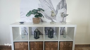 A white console table with a woven basket, a bird sculpture, and a plant. There are three glass bottles and two lanterns on the shelves. - Pleasant apartment with great views JUL01 (Ayamonte)