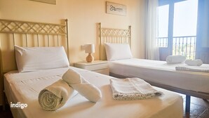 A hotel room with two beds, a nightstand with a lamp, and a window with a view. - Pleasant apartment with great views JUL01 (Ayamonte)