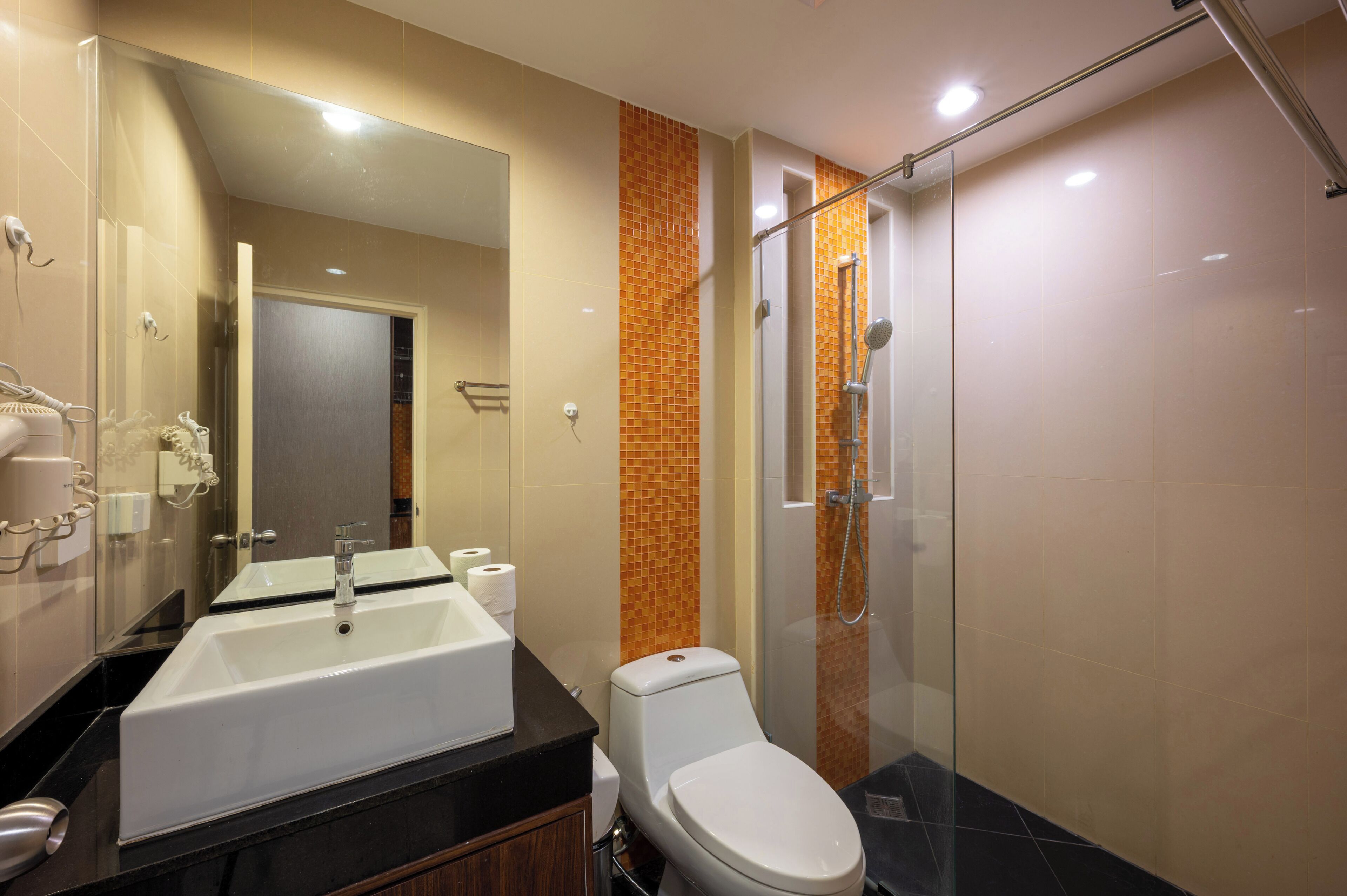 Un baño moderno con un lavamanos grande, inodoro y cabina de ducha con mampara de vidrio.