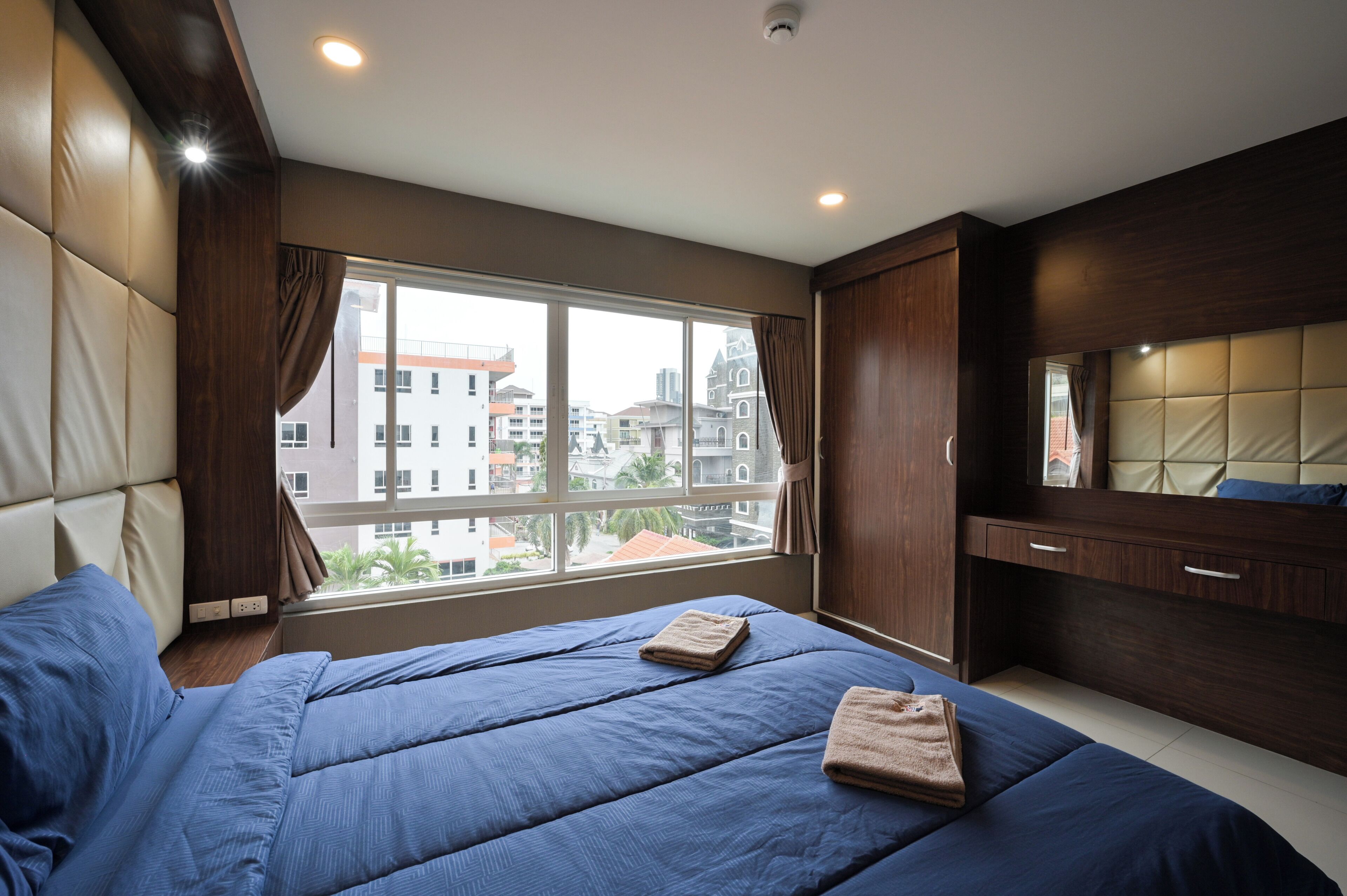 Una camera d'albergo moderna con un letto grande, un armadio e una finestra con vista sulla città.