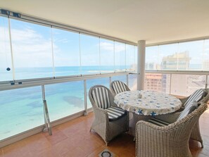 Un balcon agrémenté de meubles en osier, d’une table ronde et offrant une vue sur l’océan.