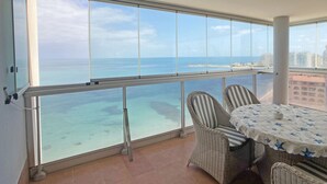Ein Balkon mit Blick auf das Meer und entfernte Gebäude.