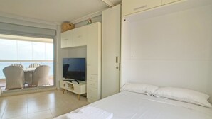 Ein Hotelzimmer mit einem Bett, einem Fernseher, einem Kleiderschrank und einer Sitzecke mit Sesseln.