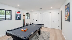 A modern room with a pool table, a poster of 'Jaws', and a 'No Smoking' sign. - 4Bdrm 3ba Pickleball, Pool Table, Nearby Marina! (Kingston)