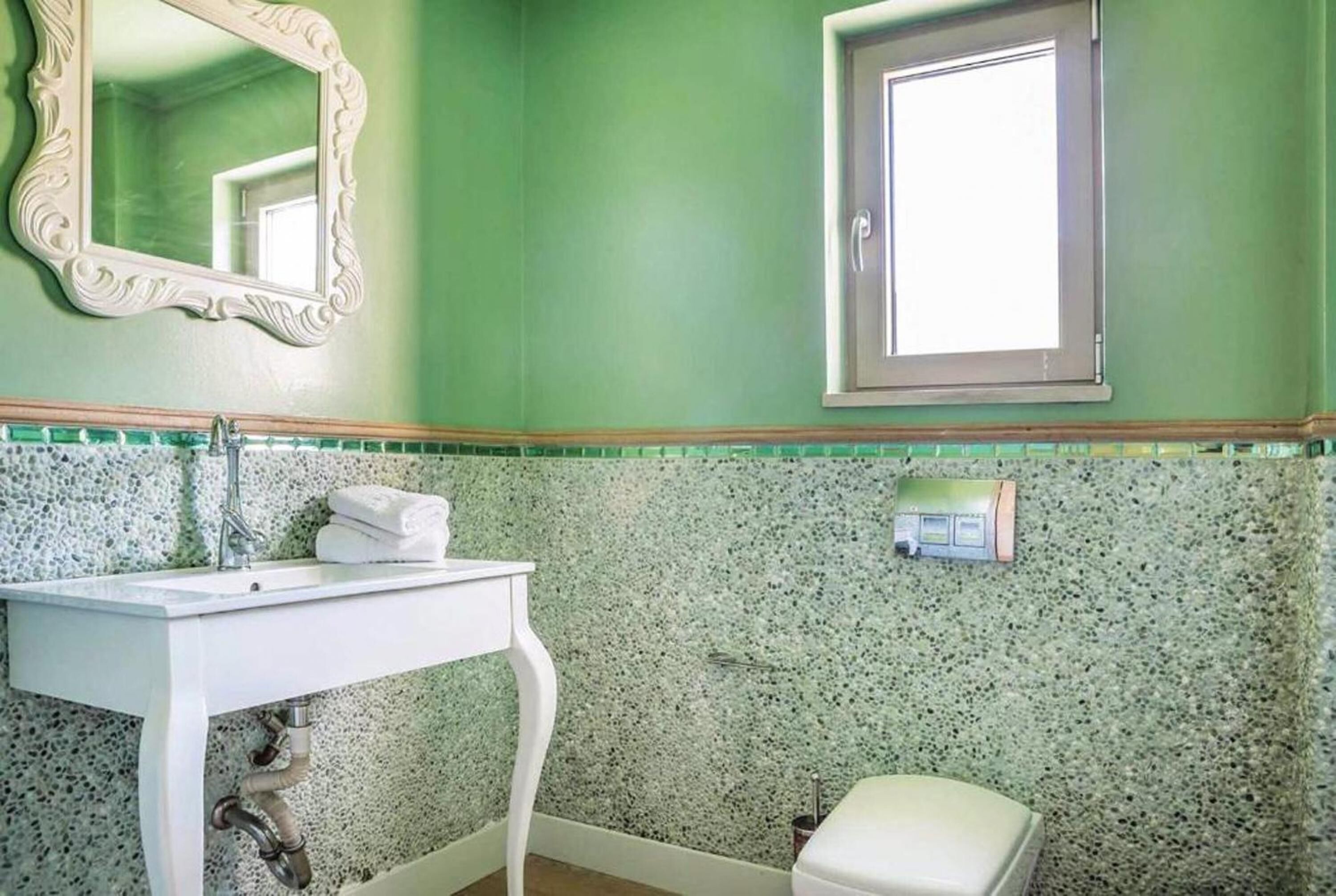 A bathroom with a white sink, a mirror, a window, and a toilet.