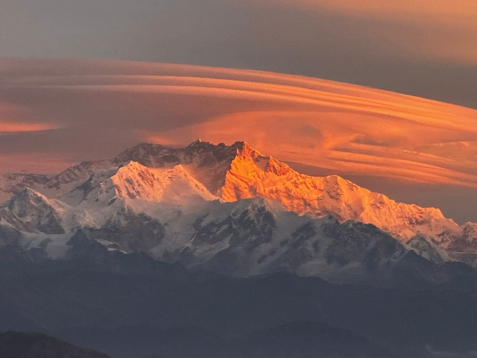 Ein Bergmassiv mit einem markanten Gipfel, der von der Sonne beschienen wird.