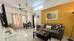 A living room with a sofa, coffee table, and a dining area with a table and chairs. - Quiet and Cozy 2 bed 1 bath in Bandra Near Ocean side
 (Mumbai)