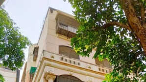 A multi-story building with a central entrance, columns, and a covered area with potted plants. - Quiet and Cozy 2 bed 1 bath in Bandra Near Ocean side
 (Mumbai)