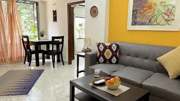 A living room with a sofa, coffee table, and dining area. - Quiet and Cozy 2 bed 1 bath in Bandra Near Ocean side
 (Mumbai)