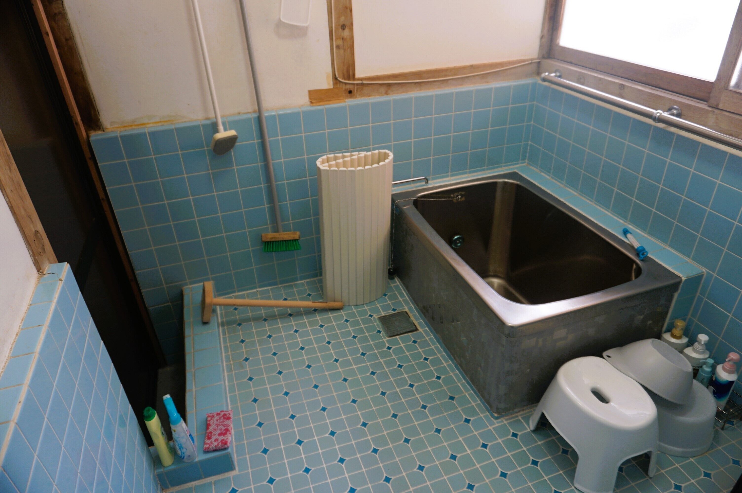 A bathroom with a bathtub, toilet, and cleaning supplies.