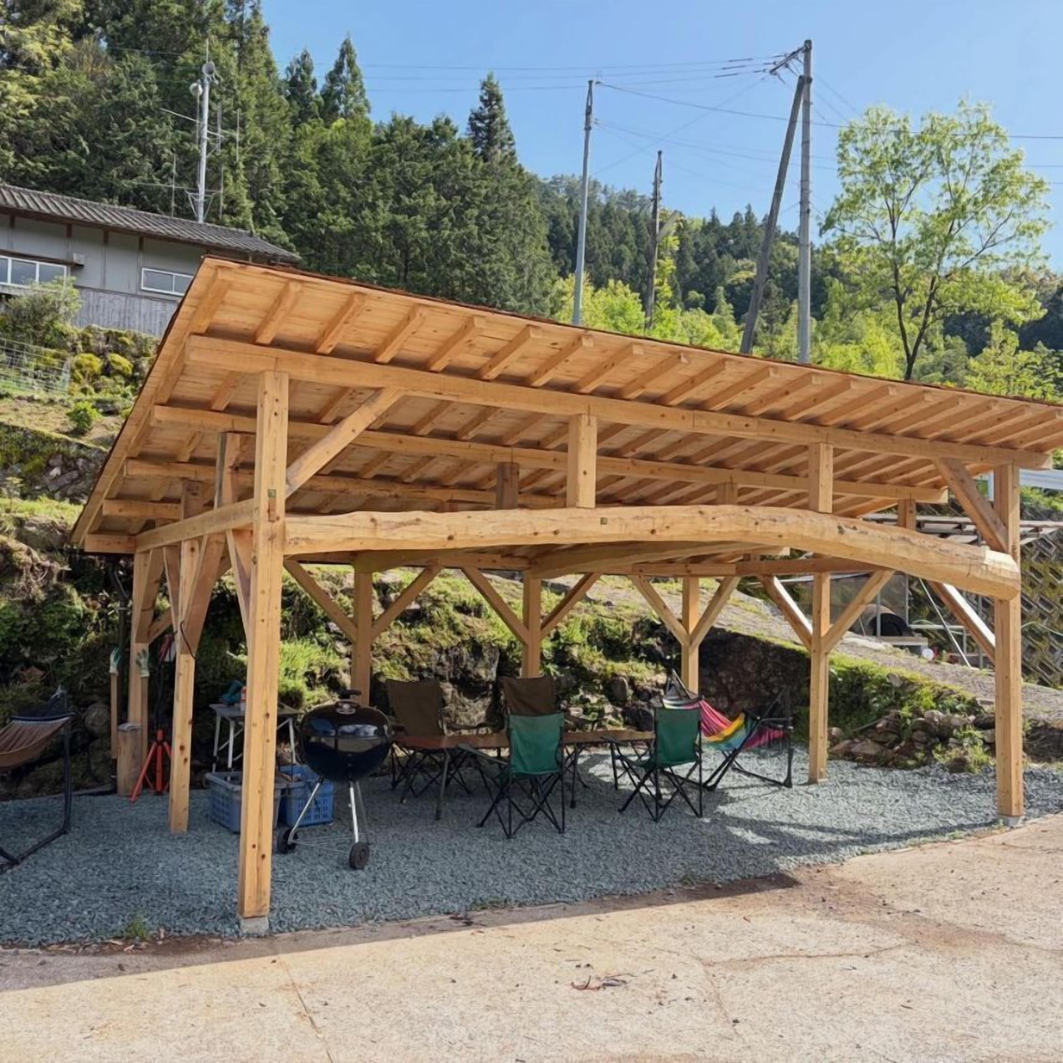 A wooden pergola structure with seating and a grill area.