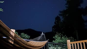 A hammock on a deck with a night sky view.