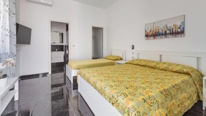 A bedroom with two beds, a TV, a painting, and a bathroom visible through an open door. - 3877 Dalie - Monolocale by Barbarhouse (Manduria)