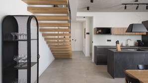 Eine moderne Küche mit Kochinsel, einer Holztreppe und einer schwarzen Dunstabzugshaube.
