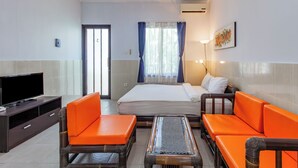 A hotel room with a bed, orange seating, a TV, and a window with curtains. - Belvilla Aranya Sanur Beach (Denpasar)