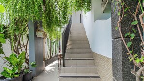 A staircase with potted plants on either side, leading to a landing. - Belvilla Aranya Sanur Beach (Denpasar)