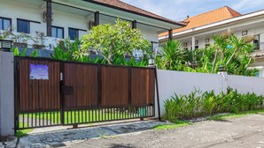 A gated residential area with a white building, a red-tiled roof, and lush greenery. - Belvilla Aranya Sanur Beach (Denpasar)