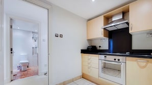 A modern kitchen with light-colored cabinets, a black countertop, and a built-in oven.