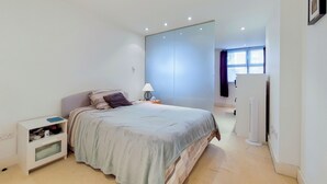 A modern bedroom with a bed, bedside table, and a nightstand.